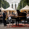 Ein Mann sitzt am Klavier und spielt Jazz-Musik, daneben steht ein weiterer Mann, der auf einem Saxophon musiziert.